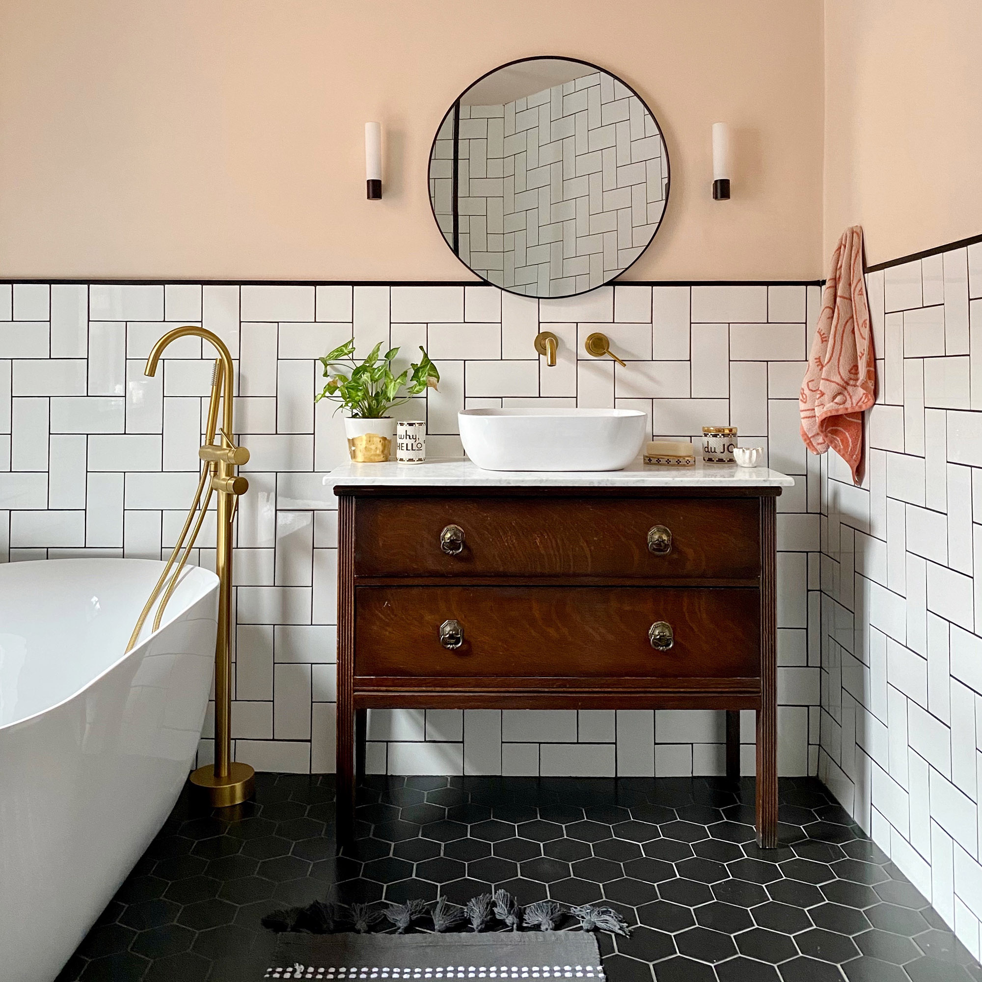 Baño moderno con paredes rosas, azulejos blancos y baldosas negras. Lavabo de estilo vintage