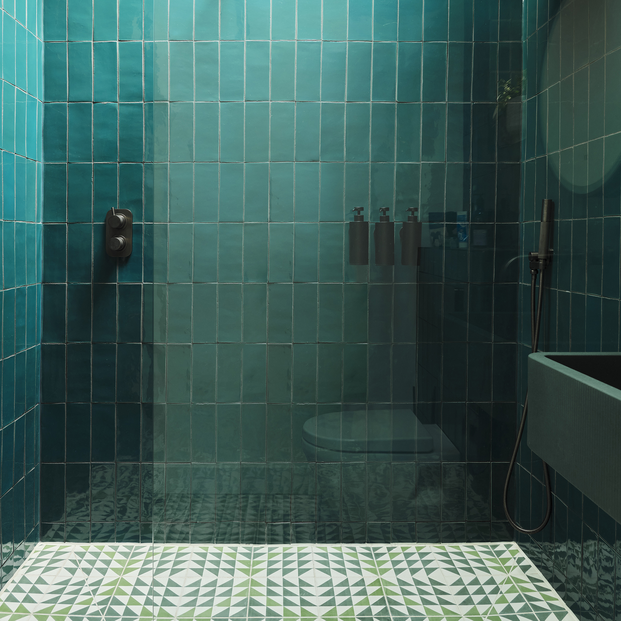 Azulejos de pared de color verde esmeralda en una ducha con azulejos verdes estampados en el suelo