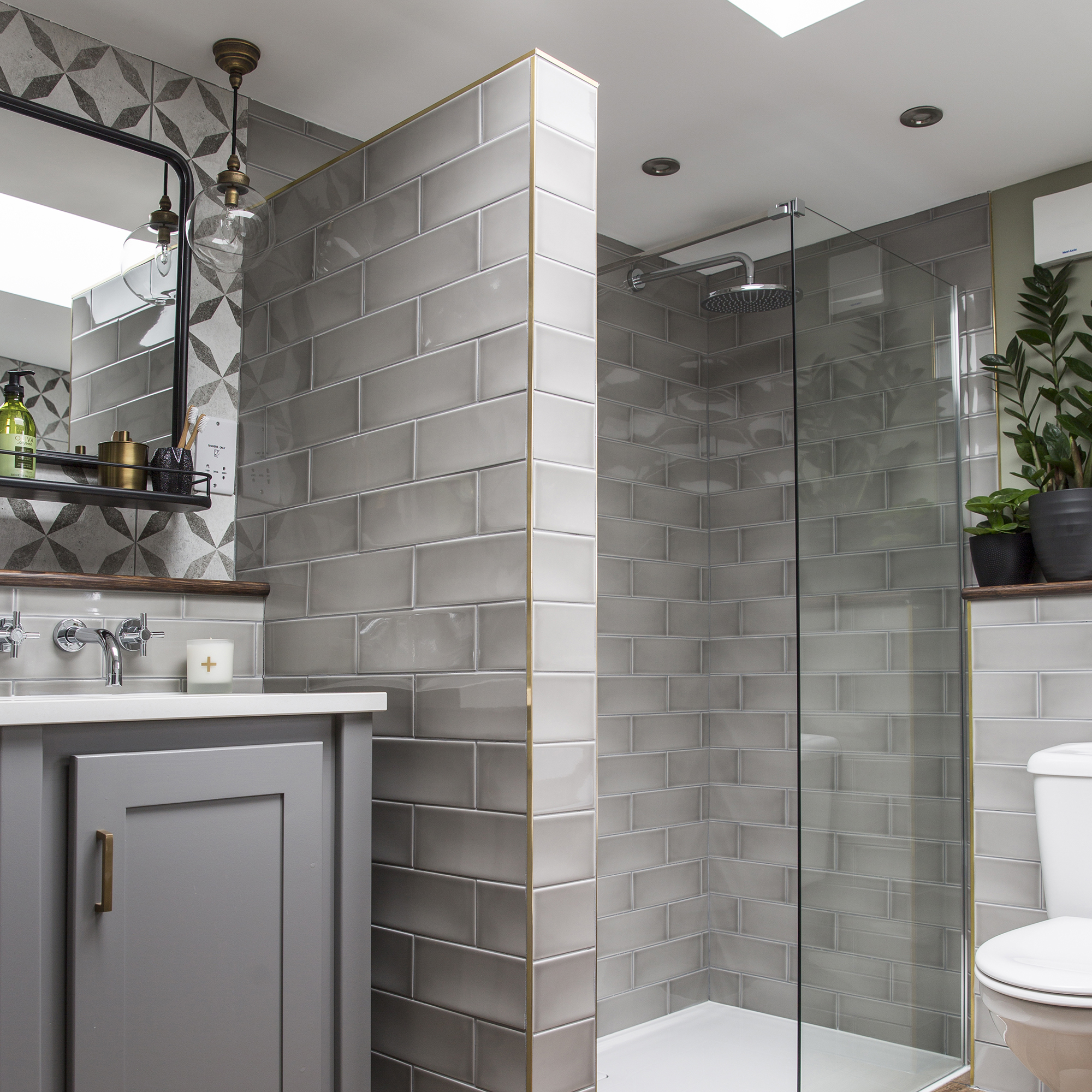 iluminacion en duchas: baño gris con mampara para ducha a ras de suelo y baldosas de metro grises
