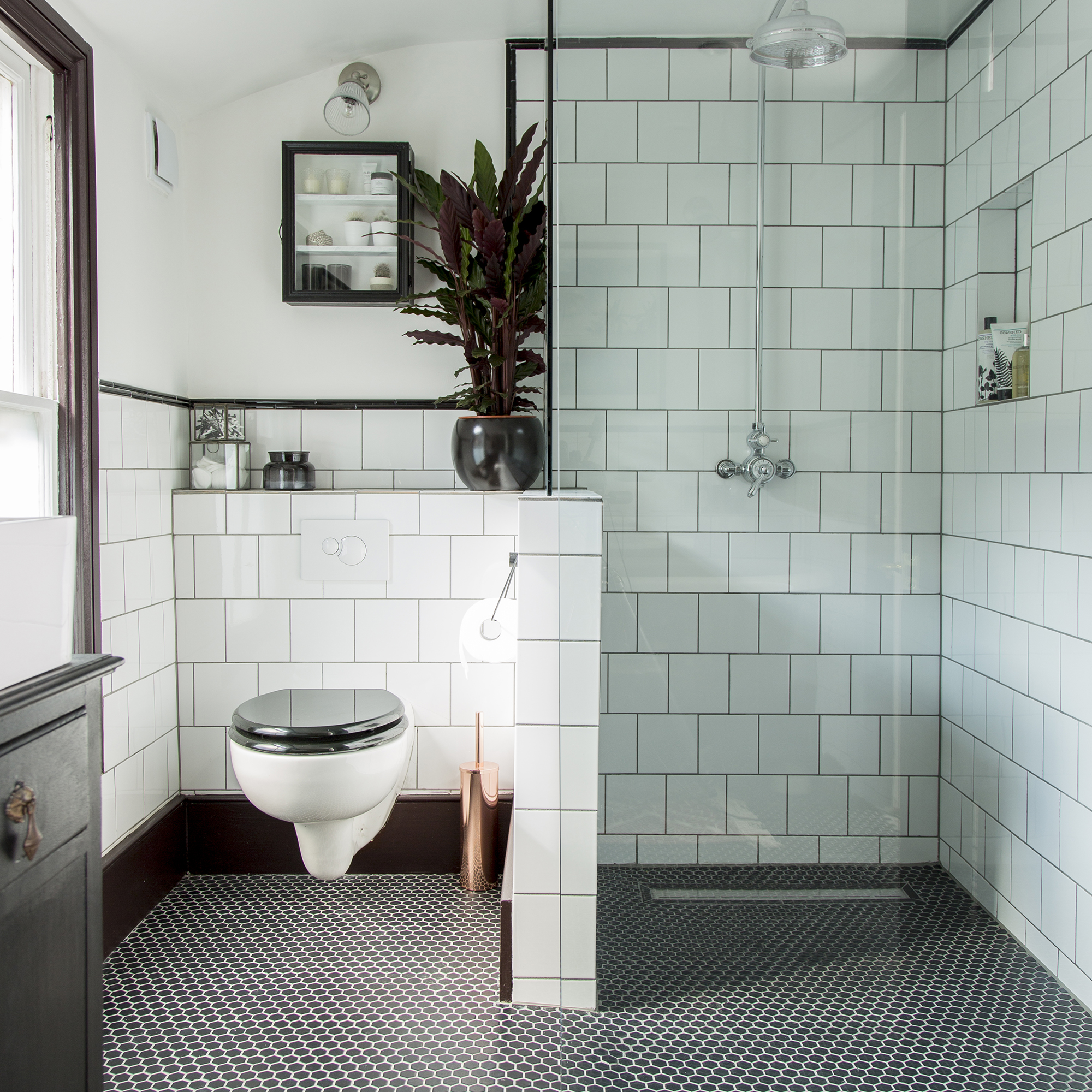 baño en blanco y negro con azulejos blancos y suelo de mosaico negro